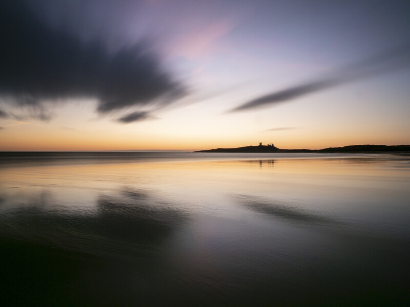 Serene waterscape at twilight with motion-blurred foreground and dramatic sky.