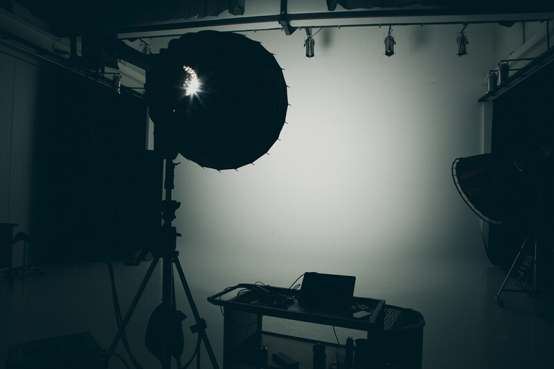 Professional studio setup with large softbox key light positioned above a workspace containing a laptop and desk.