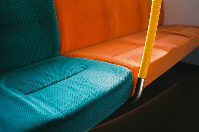 Close-up of colorful public transit seating with turquoise, orange, and yellow fabric panels.