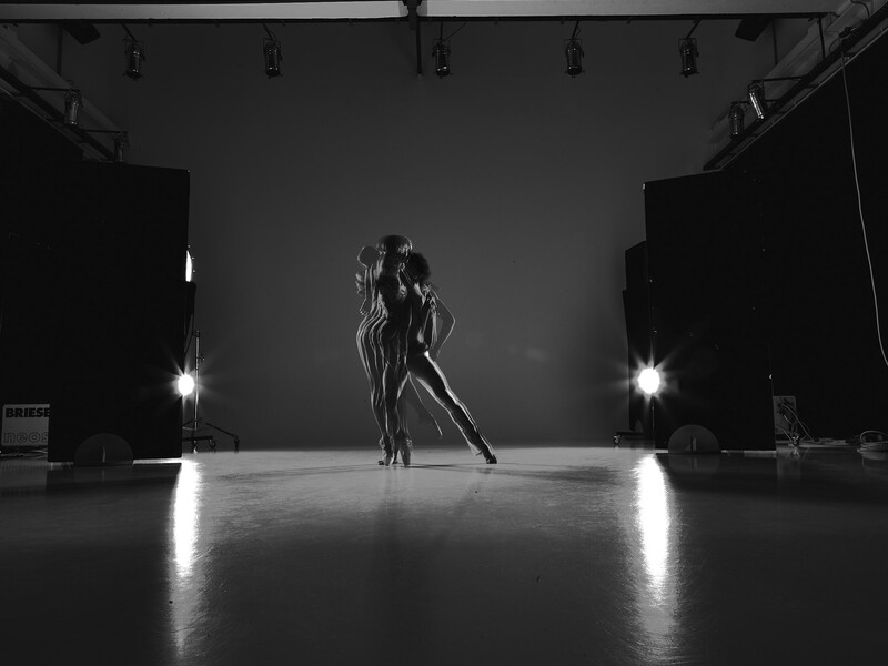 Dancer in dramatic studio lighting with strong side-lit silhouette against dark background.