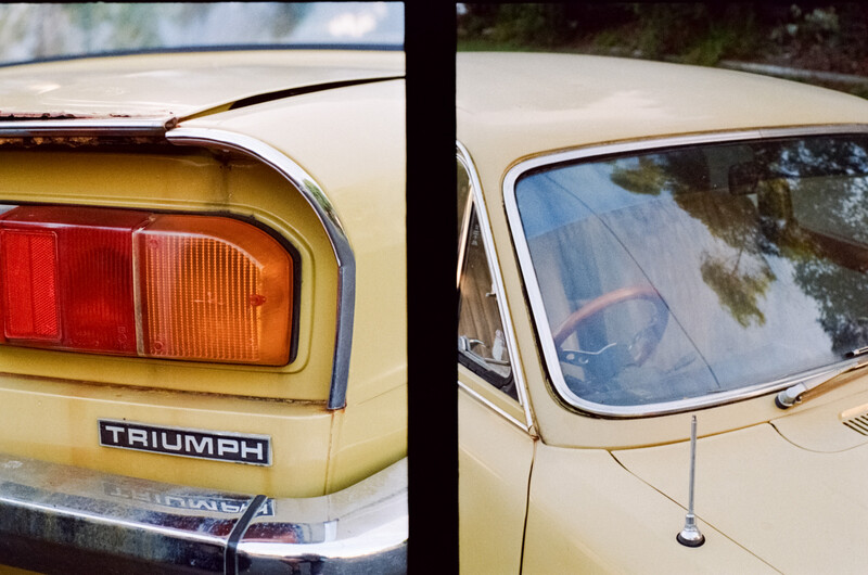 Close-up details of a vintage Triumph car showing rear taillight and side window with chrome trim.