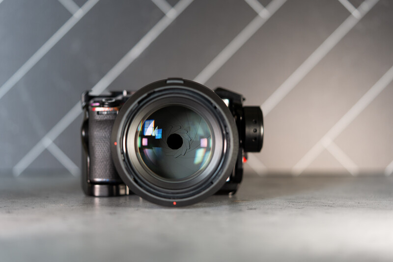 Professional camera with prime lens mounted on gray surface against diagonal striped background.