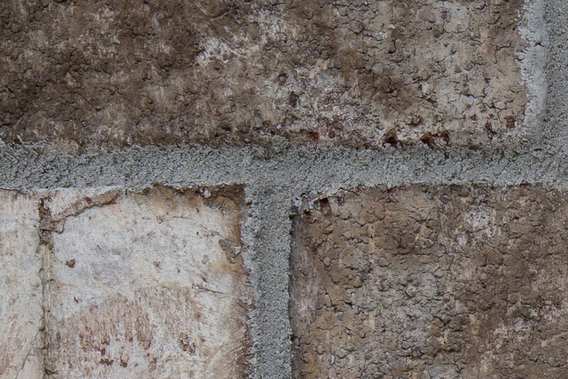 Close-up of weathered concrete blocks showing varied surface textures, stains, and deterioration patterns.