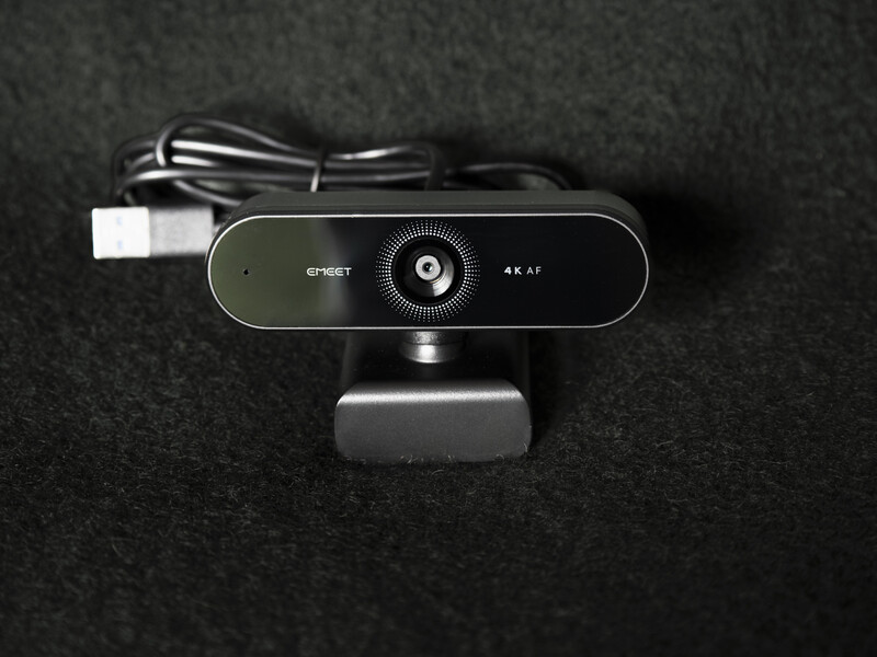 4K webcam with wide-angle lens mounted on black stand against dark textured background.