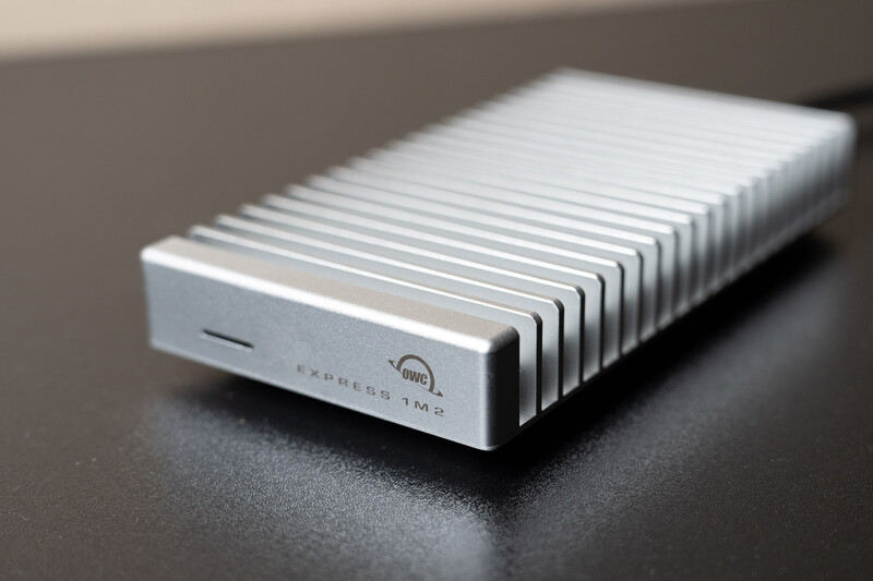 Silver external hard drive with vertical ribbed heatsink design on dark surface.