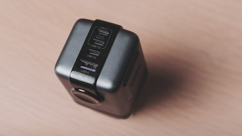 Compact camera flash or lighting unit with multiple buttons and controls on its top panel.