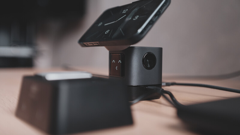 Compact black camera mounted on a stand with a remote control positioned above it.