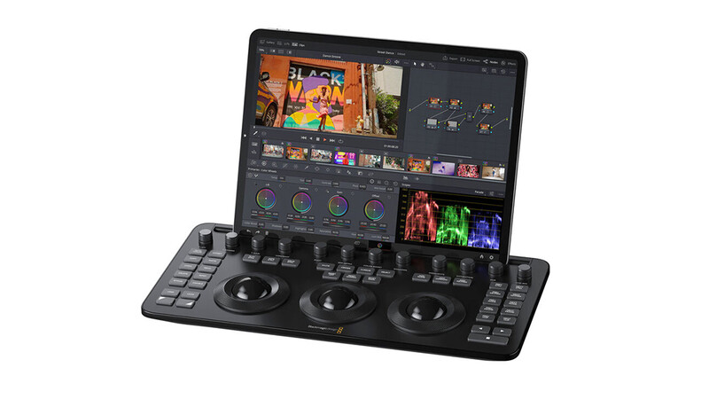 Professional video mixing controller with dual jog wheels and integrated iPad display showing editing software interface.