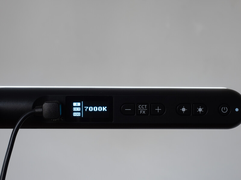 Close-up of a black LED light panel showing a digital display reading 7000K color temperature with control buttons and adjustment dials.