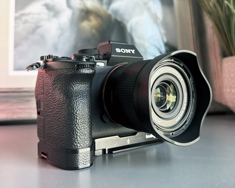 Sony mirrorless camera with battery grip and wide-angle lens mounted on desk.