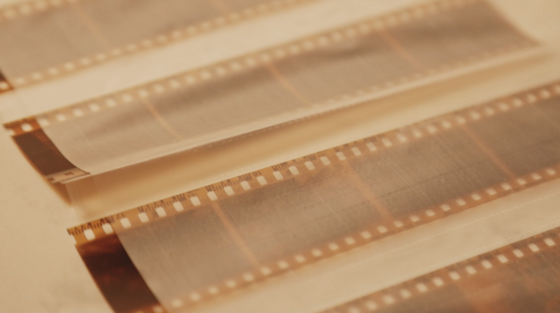 Overlapping strips of 35mm film negative arranged diagonally with warm backlighting.