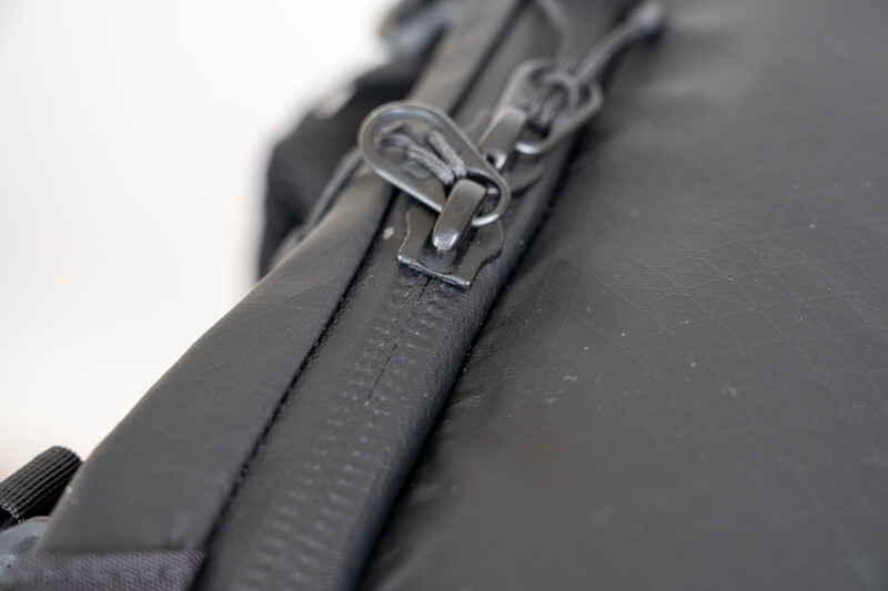 Close-up of a metal zipper slider on dark fabric with shallow depth of field.