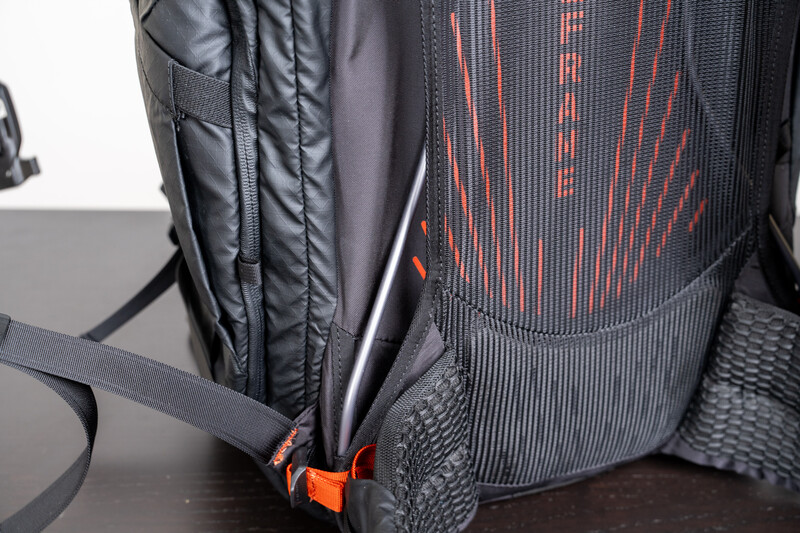 Close-up of a black and orange camera backpack showing padded compartments and orange zipper pulls.