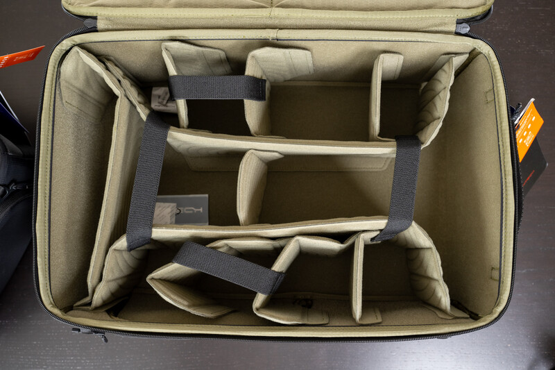 Open camera equipment case with tan dividers and compartments for storing lenses and accessories.