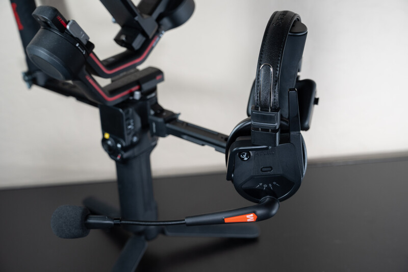 Gimbal stabilizer with mounted smartphone and wireless microphone on black surface.