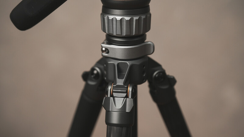 Close-up of a tripod head with pan-tilt mechanism and attached microphone boom arm.