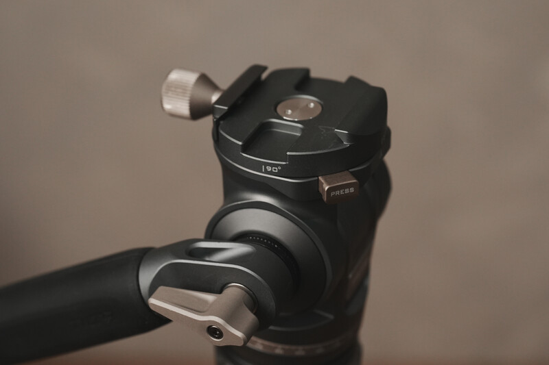 Ball head tripod mount with pan-tilt adjustment knobs and quick-release plate attached to a black support arm.