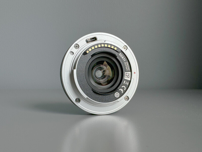 Front view of a white-bodied camera lens with glass elements visible through the center aperture.