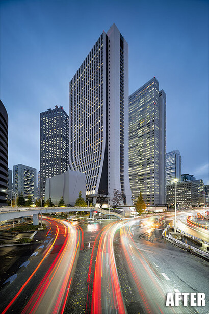 Modern urban skyline at dusk with light trails from vehicle traffic streaking across foreground.