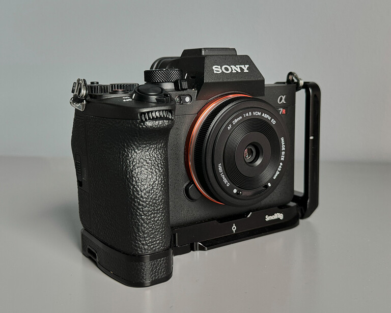 Sony mirrorless camera with battery grip and wide-angle lens mounted on L-bracket against neutral background.