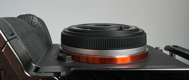 Mirrorless camera body with standard zoom lens mounted, shown from above against a neutral background.