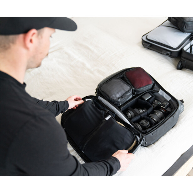 Photographer organizing camera gear and accessories in a black protective case.