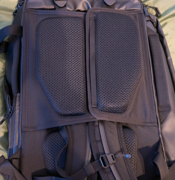 Blue-grey camera backpack with mesh ventilation panels and multiple compartments displayed flat.