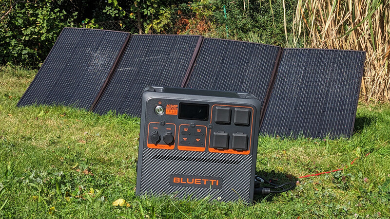 Portable power station with foldable solar panels deployed on grass outdoors.