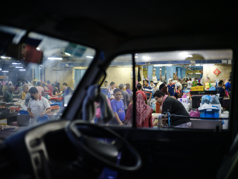 View through a car windshield of a crowded indoor event or venue with many people gathered.