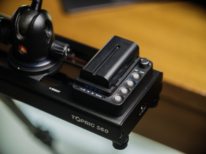 Toprig 560 audio interface with headphone amplifier mounted on black equipment stand against warm yellow backdrop.