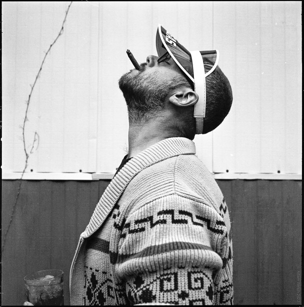 Man in striped sweater viewed from behind, head tilted upward with vintage headphones on.