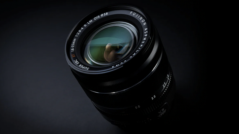 Black camera lens with multi-coated glass elements visible through the front, shot against a dark background.