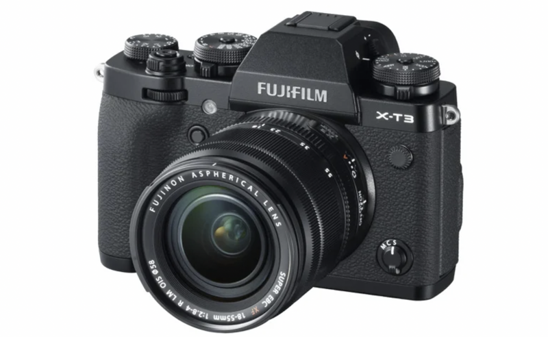 Fujifilm X-T3 mirrorless camera with attached 18-55mm lens, shown from front three-quarter angle against white background.