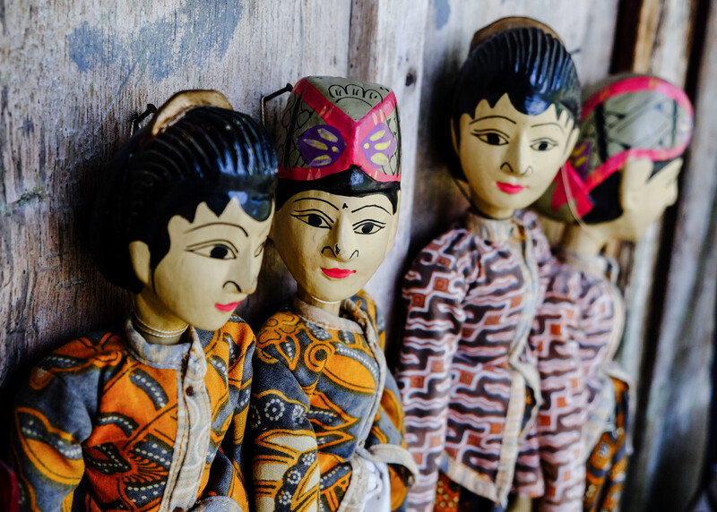Wooden hand-carved puppet dolls with painted faces and traditional patterned clothing arranged in a row.