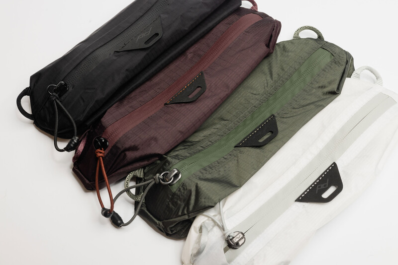 Four padded camera lens pouches in black, burgundy, olive green, and white arranged in a row.