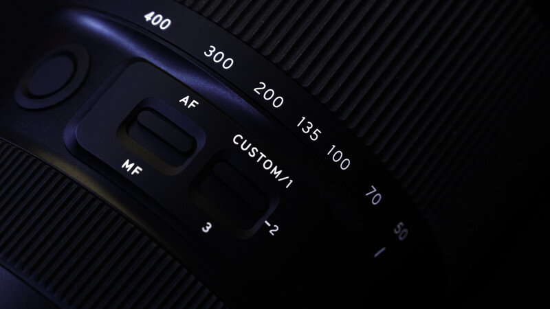 Close-up of a camera lens showing aperture scale markings from f/2.8 to f/400 with MF and AF focus mode indicators.