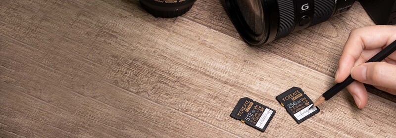 Two SanDisk memory cards displayed on a wooden surface next to camera lenses.