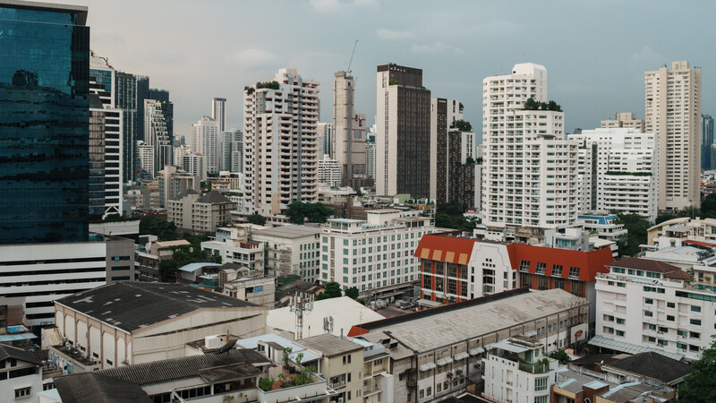 Urban cityscape with dense high-rise buildings and a distinctive red-orange building in the mid-ground.
