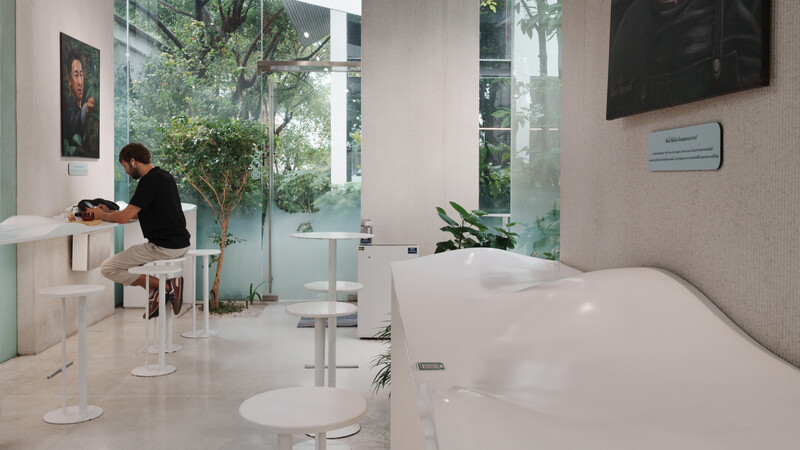 Modern medical office reception area with white furnishings, large windows overlooking greenery, and a receptionist at desk.