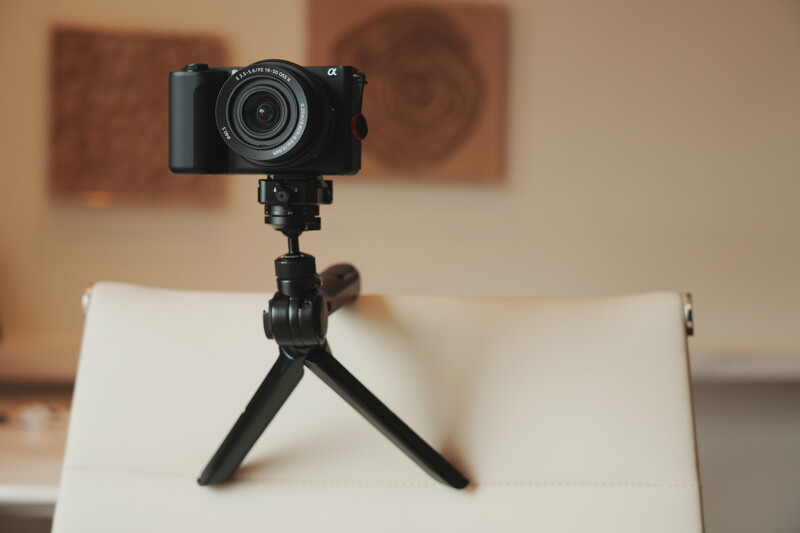 Compact mirrorless camera mounted on a small black tripod with articulating legs.