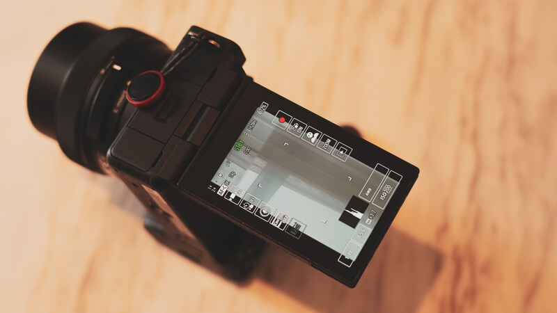 Mirrorless camera displayed from above on wooden surface with articulating screen visible.
