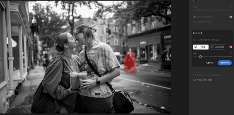 Two people embracing on an urban street in black and white, with a blurred red object in the background.
