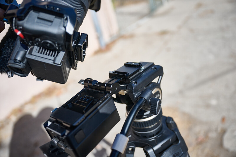 Professional camera mounted on a tripod head with articulating arm in outdoor sunlight.