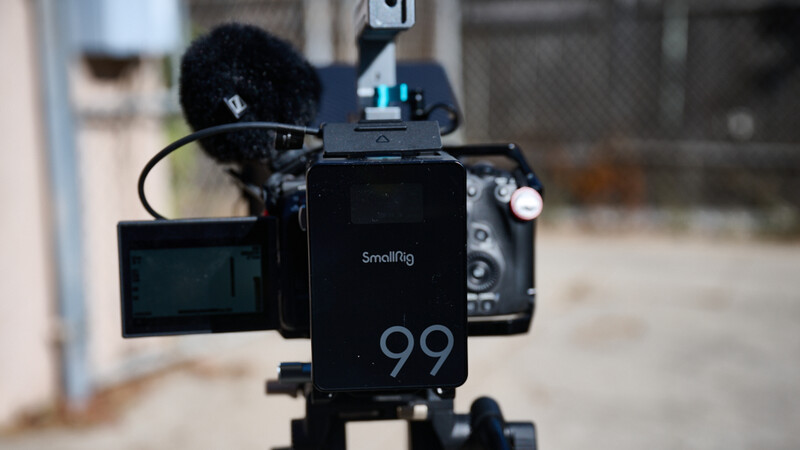 Smallrig cinema camera rig with external monitor and wireless microphone mounted on tripod.