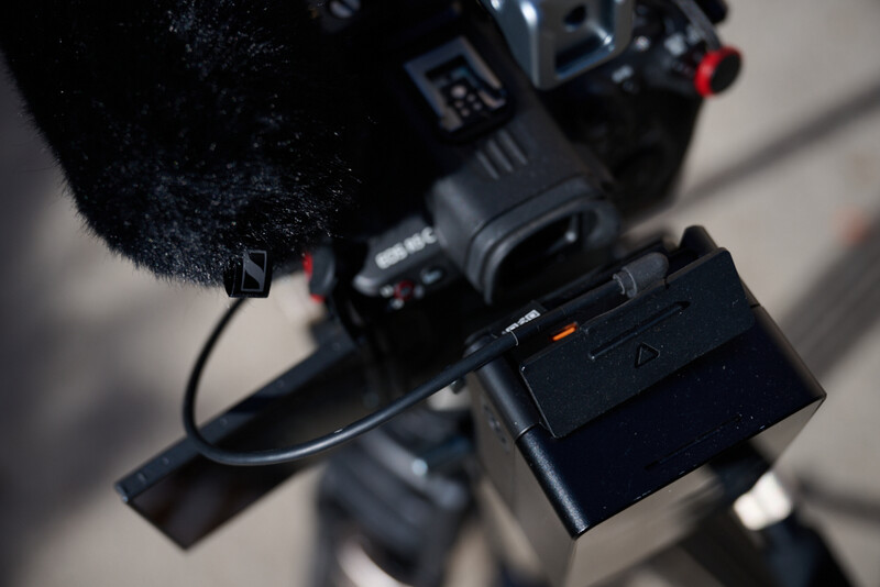 External recorder and battery pack mounted on cinema camera with windscreen microphone.