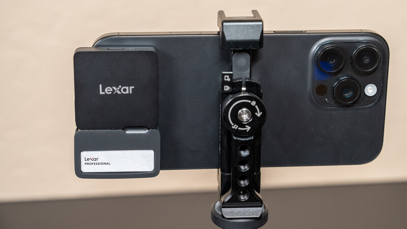 iPhone mounted on a smartphone gimbal stabilizer with Lexar storage accessory attached.