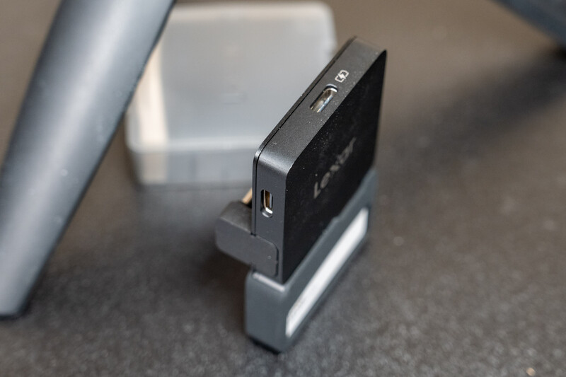 External hard drive and docking station displayed on gray surface with metallic pipe visible.