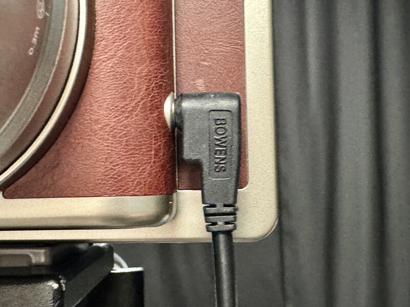 Close-up of a USB power cable connector attached to brown leather camera equipment.