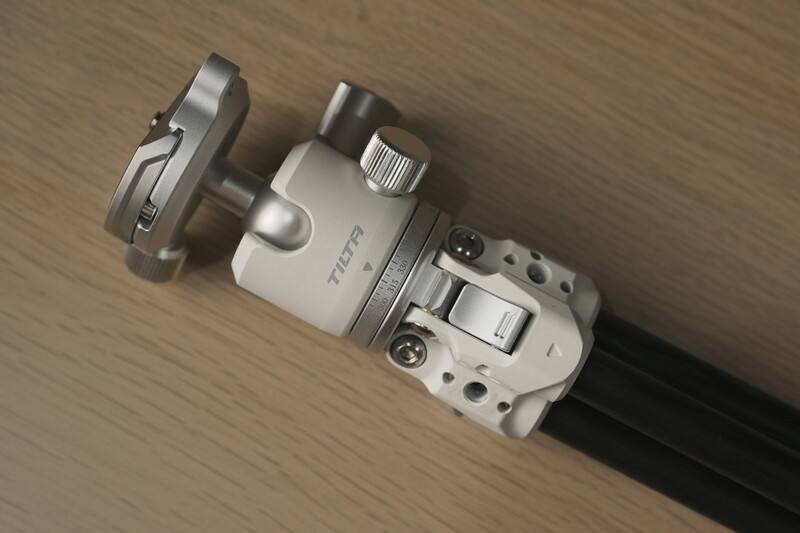 Top-down view of a compact camera with external microphone and accessories mounted on a wooden surface.