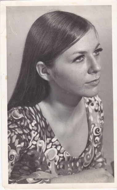 Profile portrait of a woman with long dark hair wearing a patterned garment.